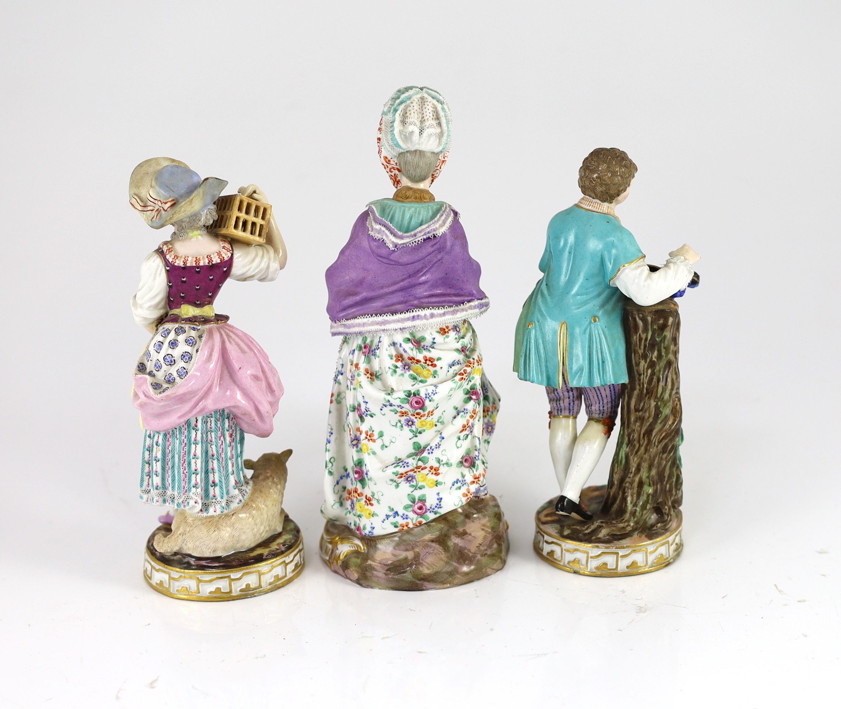 A pair of Meissen figures of a youth with a bird’s nest and a maiden holding a bird in a cage and a Meissen figure of a lady with a muff, 19th century, 18.5 - 20.5cm high, some restoration and losses